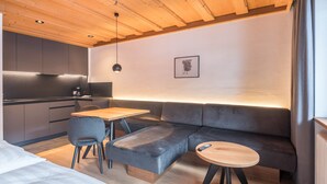 Una habitación moderna con techo de madera, un sofá, una mesa y una silla.