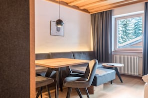 A modern room with a wooden ceiling, a sofa, a table, and a window with curtains.
