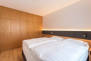 Une chambre à coucher avec un lit, une armoire en bois et un luminaire fixé au mur.