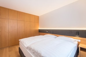 Une chambre d’hôtel moderne avec un grand lit, une armoire en bois et une table de chevet.