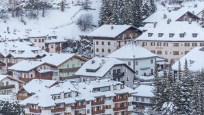 Ett snötäckt bostadsområde med flerfamiljshus, några med balkonger, och en framträdande byggnad med en skylt som visar texten ”ANRI”.