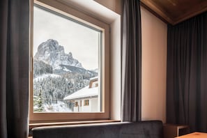 A room with a large window overlooking a snowy mountain landscape.