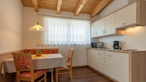 A compact kitchen with wooden cabinets, a dining table with chairs, and a pendant light. - Apartment "Wohnung 2 Dachgeschoss" with Mountain View, Wi-Fi & Balcony (Dorf Tirol)
