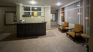 A reception area with a counter, a reception desk, and a window with curtains. There are two chairs and a small table. - Tekirova Millennium Hotel (Kemer)