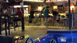 An outdoor bar area with a pool, stone walls, and a neon sign reading "Millennium Pool Bar". - Tekirova Millennium Hotel (Kemer)