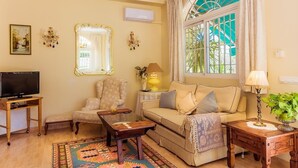 A living room with a sofa, armchair, TV, and decorative items. - Apartment "Capricho Montepino 1 Las Palomas" with Pool, Wi-Fi, A/C, Terraces & Garden (La Herradura)