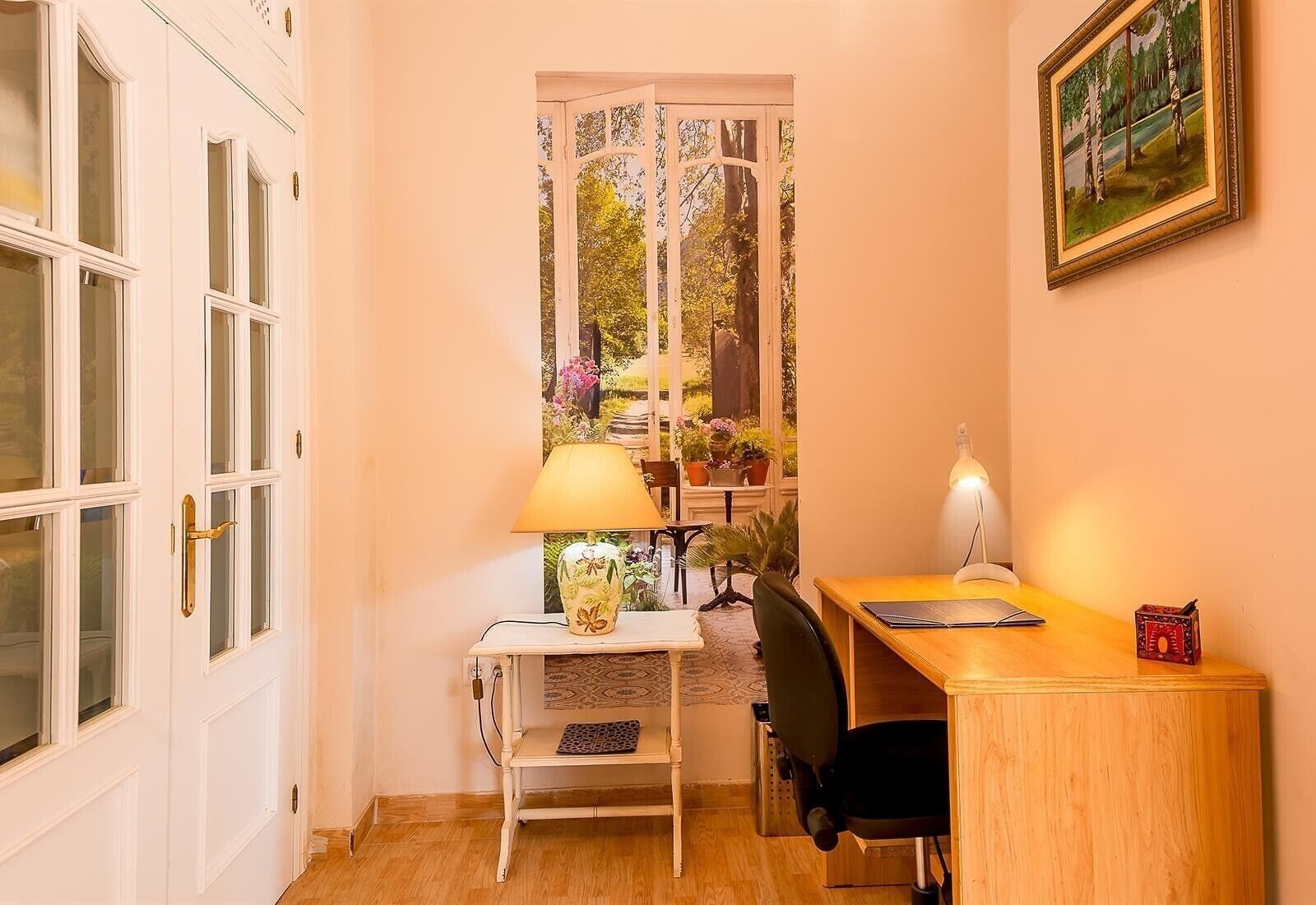 Une petite pièce comprenant un bureau, une chaise et une fenêtre donnant sur un paysage verdoyant.