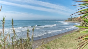 A beach with waves, a clear sky, and some vegetation. - Beach front apartment with Sea View (Estepona)