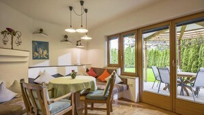 A cozy room with a wooden dining table, chairs, a bench, and a large window offering a view of the outdoors.