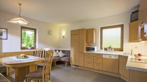 A compact kitchen with wooden cabinets, a dining table with chairs, a microwave, and a sink.