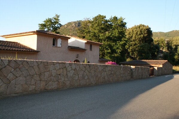 Eine steine Mauer mit einem Haus und einem Berg im Hintergrund.