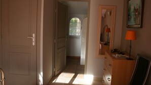 En hall med en dörr, en byrå i trä, en lampa och en tavla på väggen.