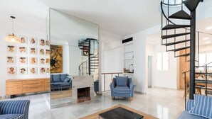 Una sala de estar moderna con una escalera espiral, una chimenea y un muro espejado.