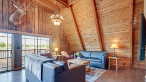 A log cabin interior with a large sofa, a coffee table, and a deer head mounted on the wall. - Lakefront A-Frame Cabin with Community Perks (Columbia)