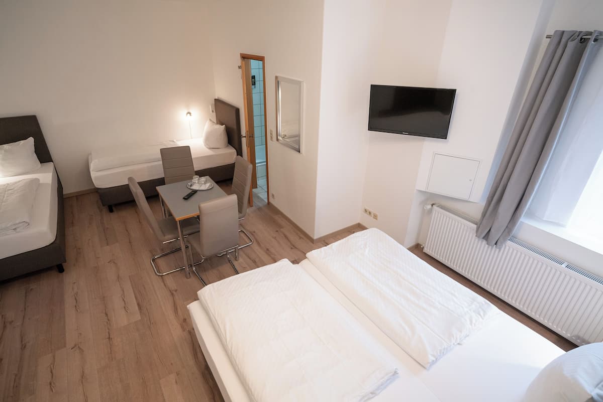 Une chambre d’hôtel avec un lit, un bureau et une chaise, une télévision et une fenêtre avec des rideaux.