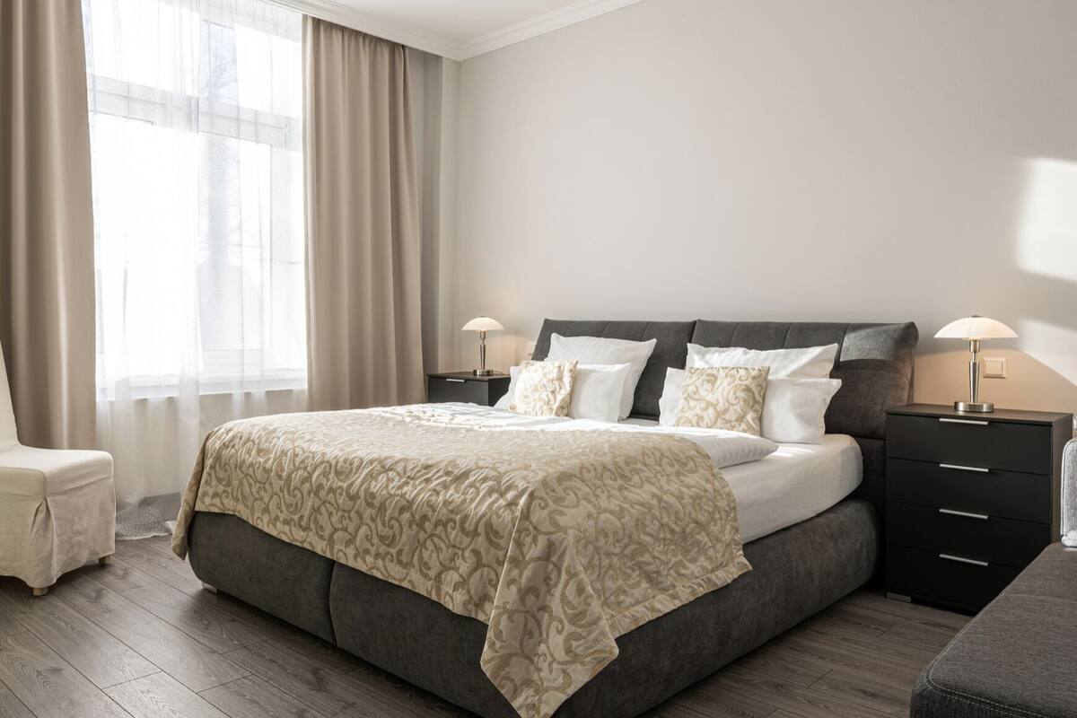 Une chambre à coucher bien aménagée, avec un grand lit, deux tables de chevet avec des lampes, une chaise et une armoire.