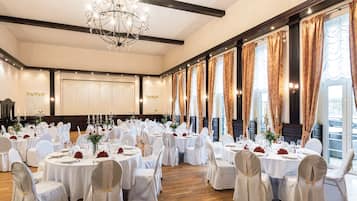 Una sala de banquetes amb taules rodones, cadires blanques i un penjall.