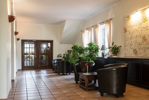 A spacious hallway with a tiled floor, a wooden door, and several potted plants.
