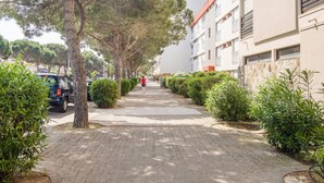 A tree-lined pathway leading to a modern building with a red roof and beige walls. - Le Liberté by Interhome (Saint Cyprien)