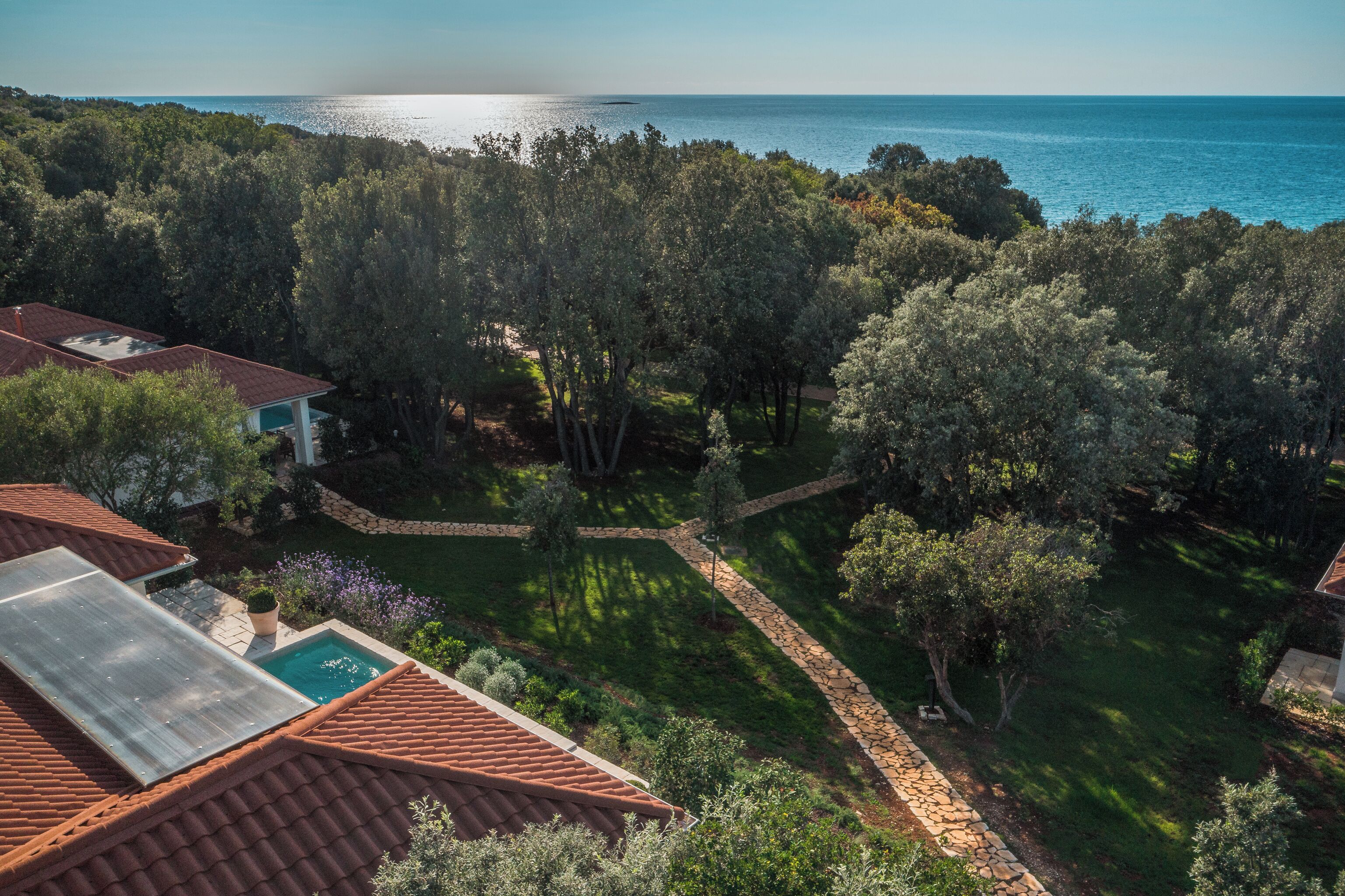 A residential property with a swimming pool, solar panels, and a view of the sea.
