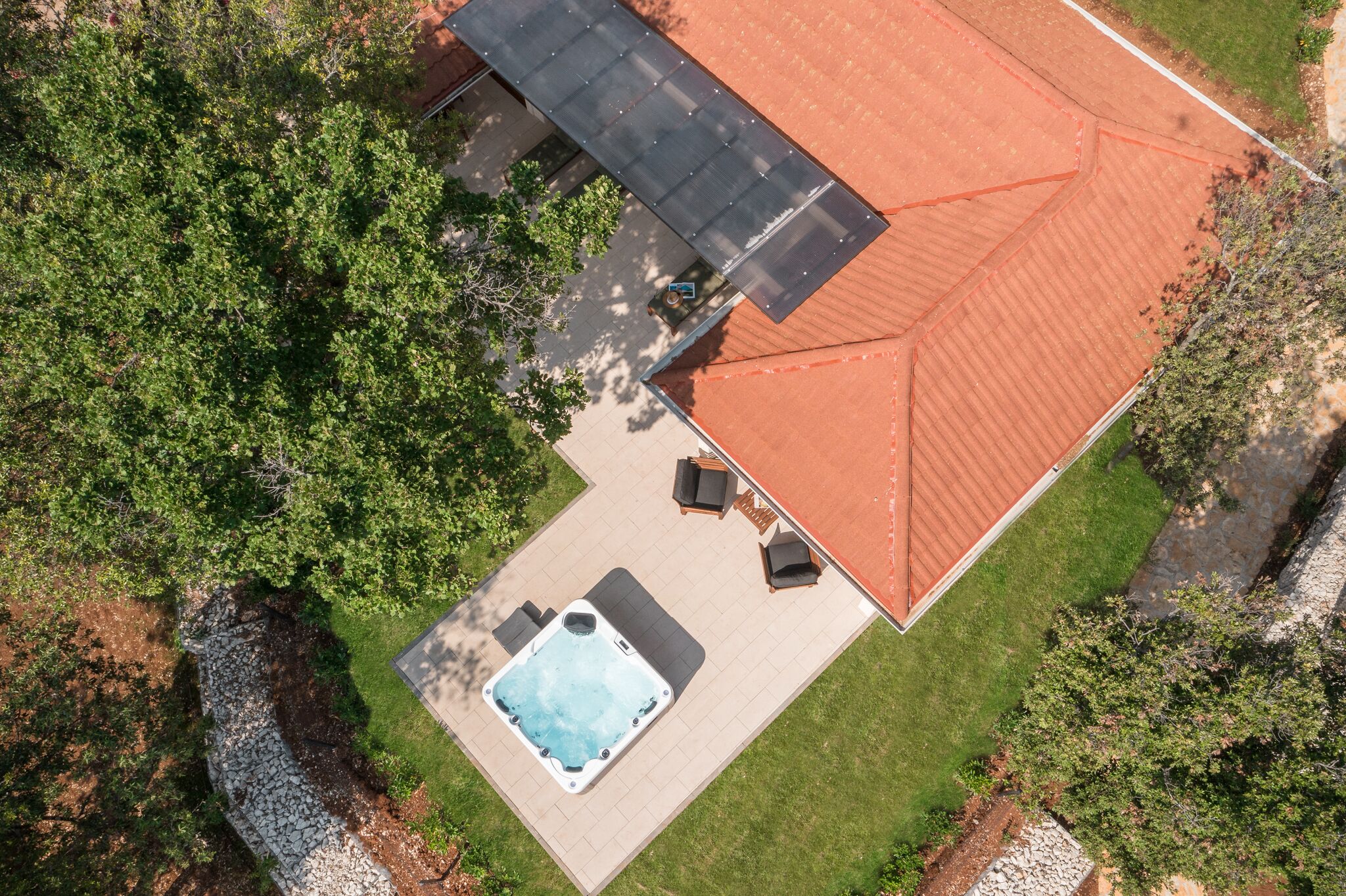 Vue aérienne d’une maison avec un toit rouge, un jacuzzi et un espace salon extérieur.