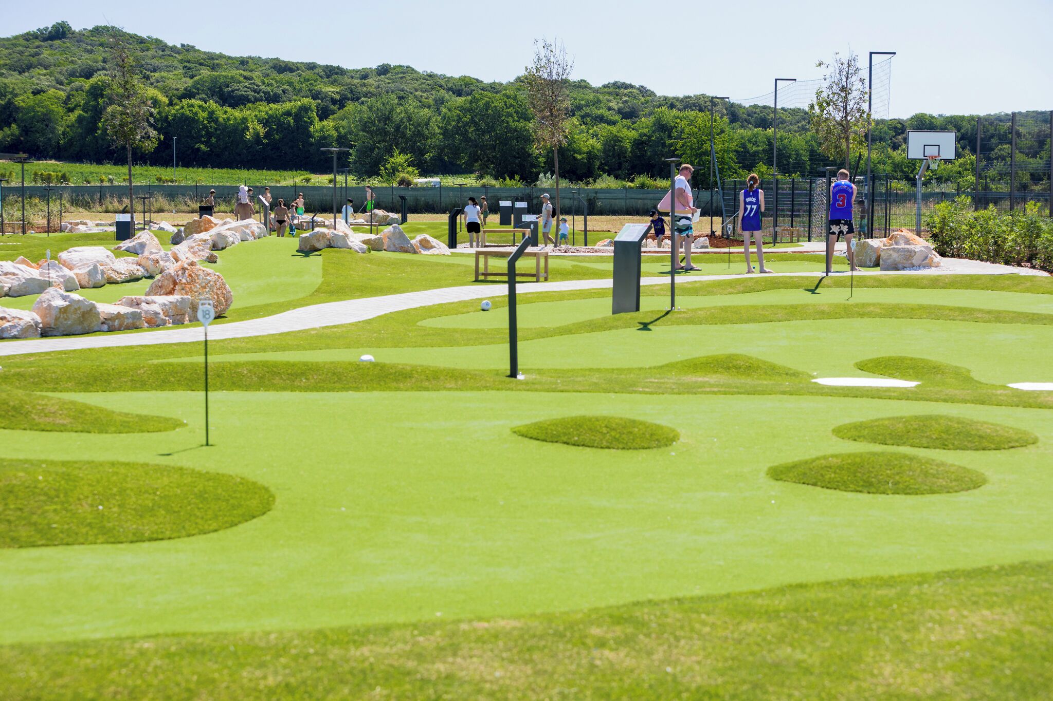 Golfkenttä, jossa on harjoitusviheriö, hiekkabunkerit ja kirkas taivas.