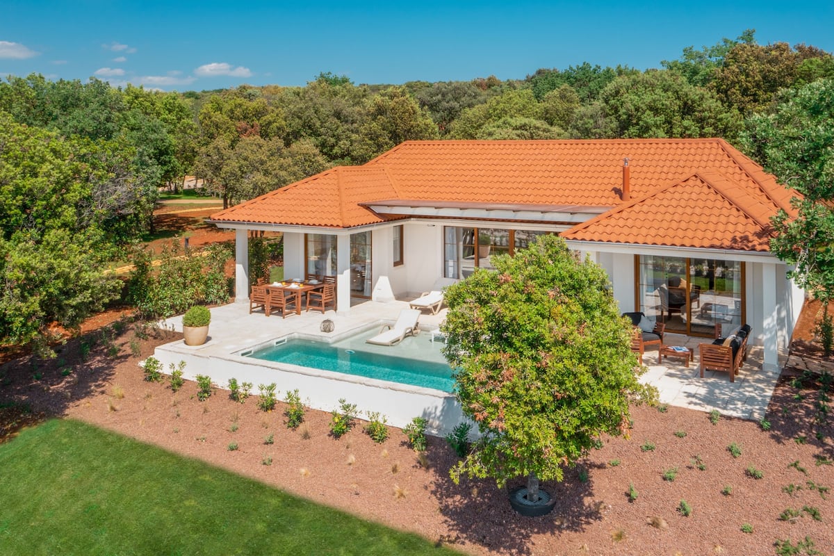 A modern house with a swimming pool, outdoor seating, and a garden.