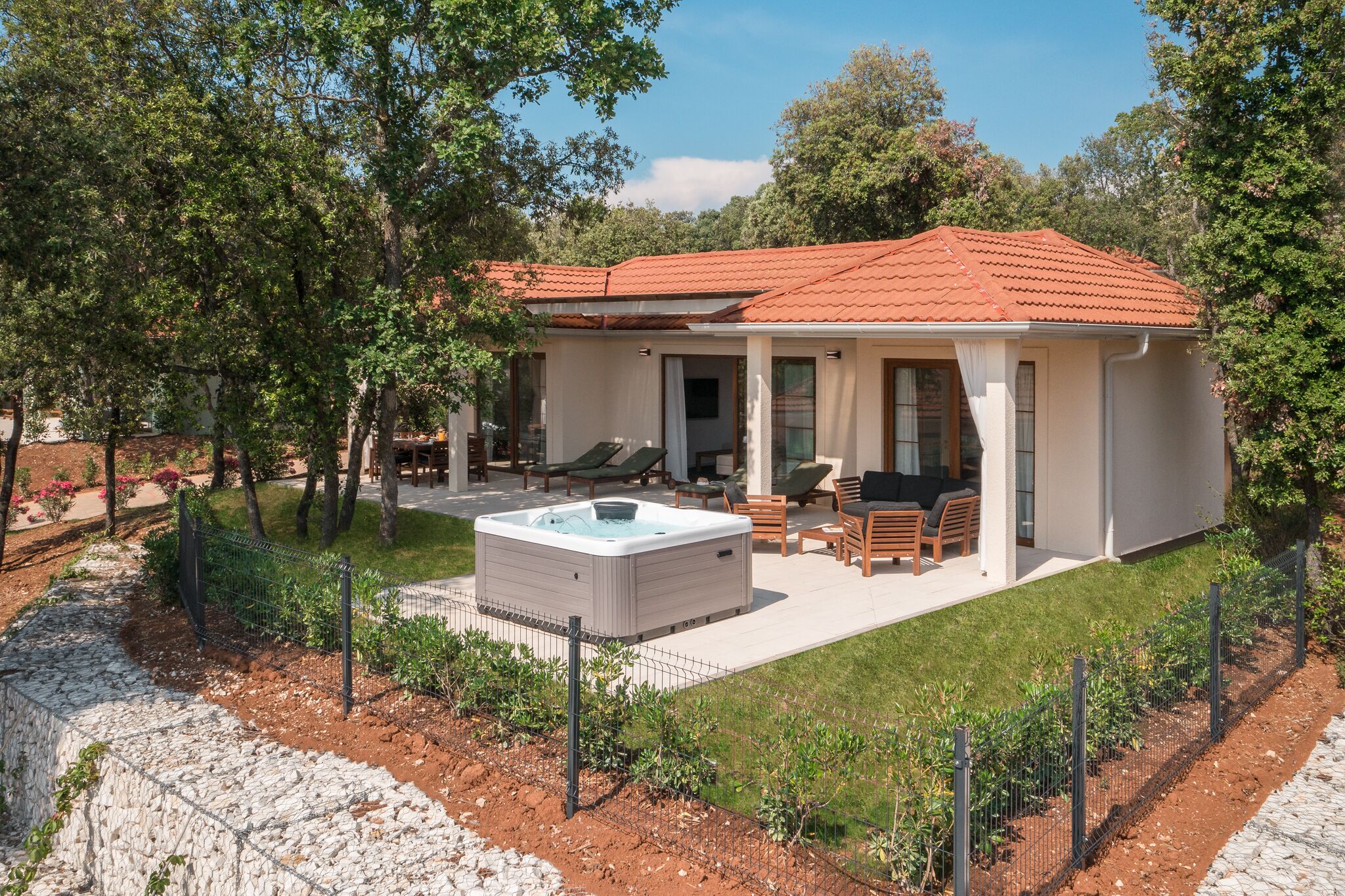 A modern house with a red-tiled roof, a hot tub, and outdoor seating.