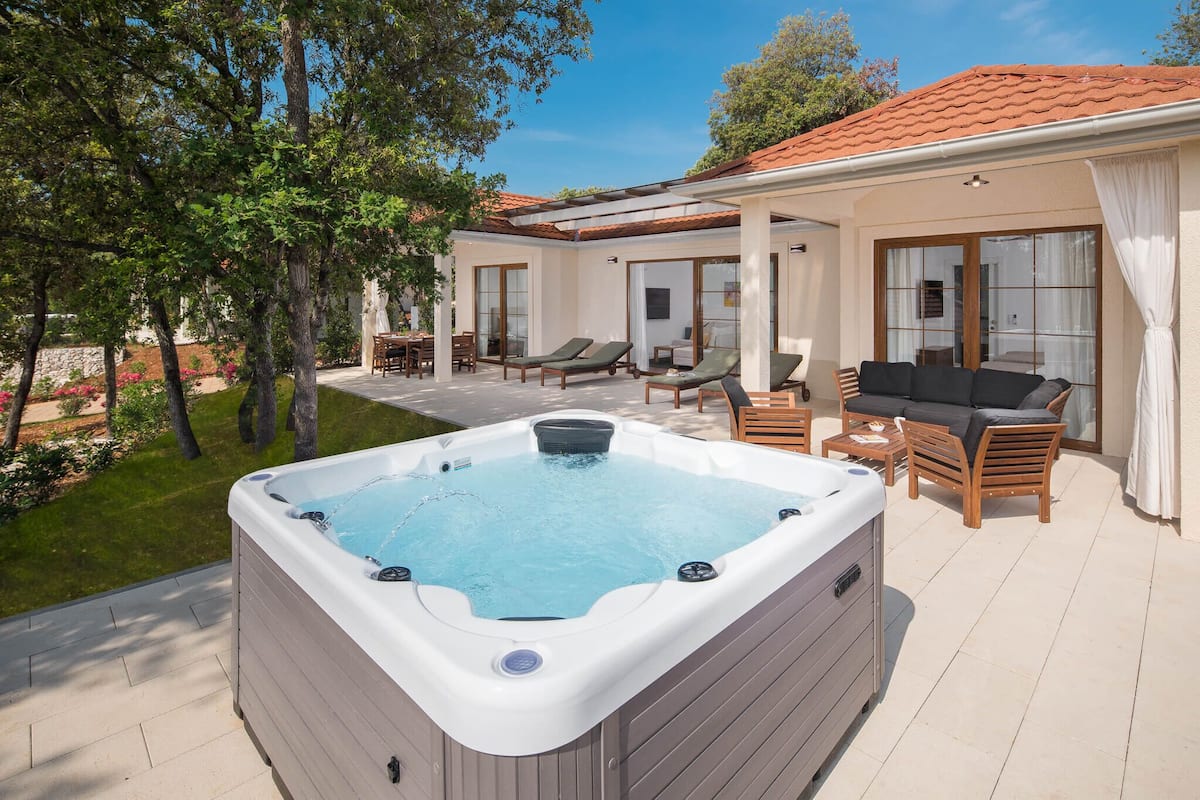 A hot tub with lounge chairs and a dining area on a patio.