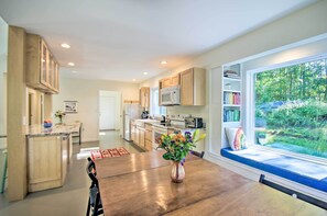 Enjoy meals in the kitchen with a central island and dining table, overlooking a garden through a large window.