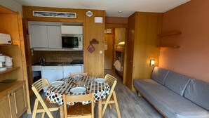 Un espace de vie compact comprenant un coin cuisine, une table à manger avec des chaises et un canapé.