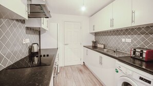 Una cucina compatta con piano di lavoro nero, lavatrice integrata e forno a microonde.