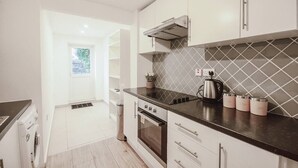 Una cucina moderna con mobili bianchi, un piano di lavoro nero e una schiena a parete rivestita di piastrelle.