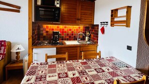 A compact kitchen with wooden cabinets, a microwave, and a coffee maker.