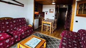 A compact living space with a sofa, a dining table, and a kitchen area.
