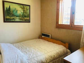 A bedroom with a bed, a window, a radiator, and a painting on the wall. - Cozy apartment in Morillon, pets allowed (Morillon Village)