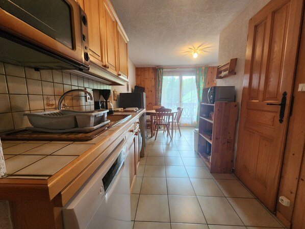 A kitchen with wooden cabinets, a tiled backsplash, a built-in oven, and a dining area with a table and chairs.