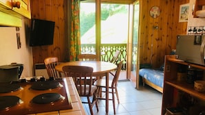 Una cucina accogliente con un tavolo da pranzo, sedie, una piccola TV e una libreria.