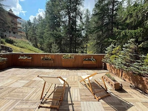 A wooden deck with two lounge chairs, surrounded by a wooden fence and dense forest. - Charming 4-room apartment for 6 at slopes' edge with wifi (Val-d'Isère)