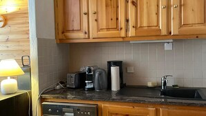 Une cuisine avec des meubles de rangement en bois, une machine à café, un grille-pain et un lave-vaisselle.