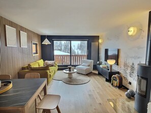 Un salon moderne avec un canapé, une table basse, un téléviseur et une cheminée.