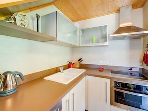 A modern kitchen with a wooden ceiling, stainless steel appliances, and white cabinetry.