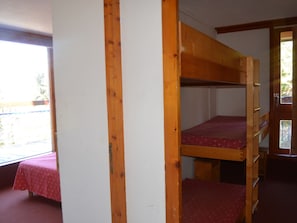 Una camera con un letto a castello, una finestra e una porta.