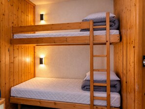 Ein Stockbett mit einer Leiter, Holzwänden und zwei Wandleuchten.