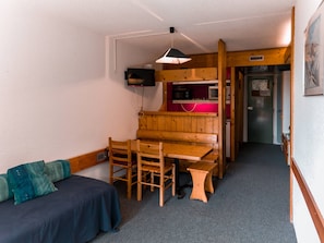 A compact room with a wooden table and chairs, a small kitchenette, a sofa, and a television mounted on the wall. - 2-room apartment for 6 people, pets allowed, Arc 1800 (Les Arcs 1800)
