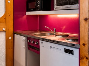 Eine kompakte Küchenzeile mit Mikrowelle, Toaster, Spüle und einem kleinen Geschirrspüler.