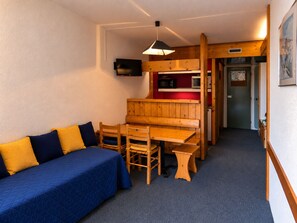 Ein kleines Zimmer mit einem Bett, einem Holztisch und einer Bank.