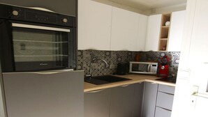 Una cocina compacta con horno empotrado, microondas y cafetera.