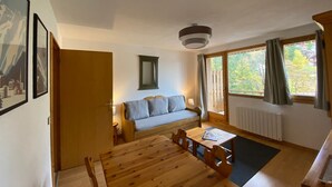 A cozy room with a wooden table, a sofa, and a window with curtains.