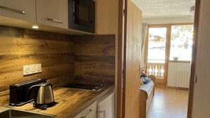 A compact kitchen with wooden cabinetry, a built-in microwave, a toaster, and a sink.